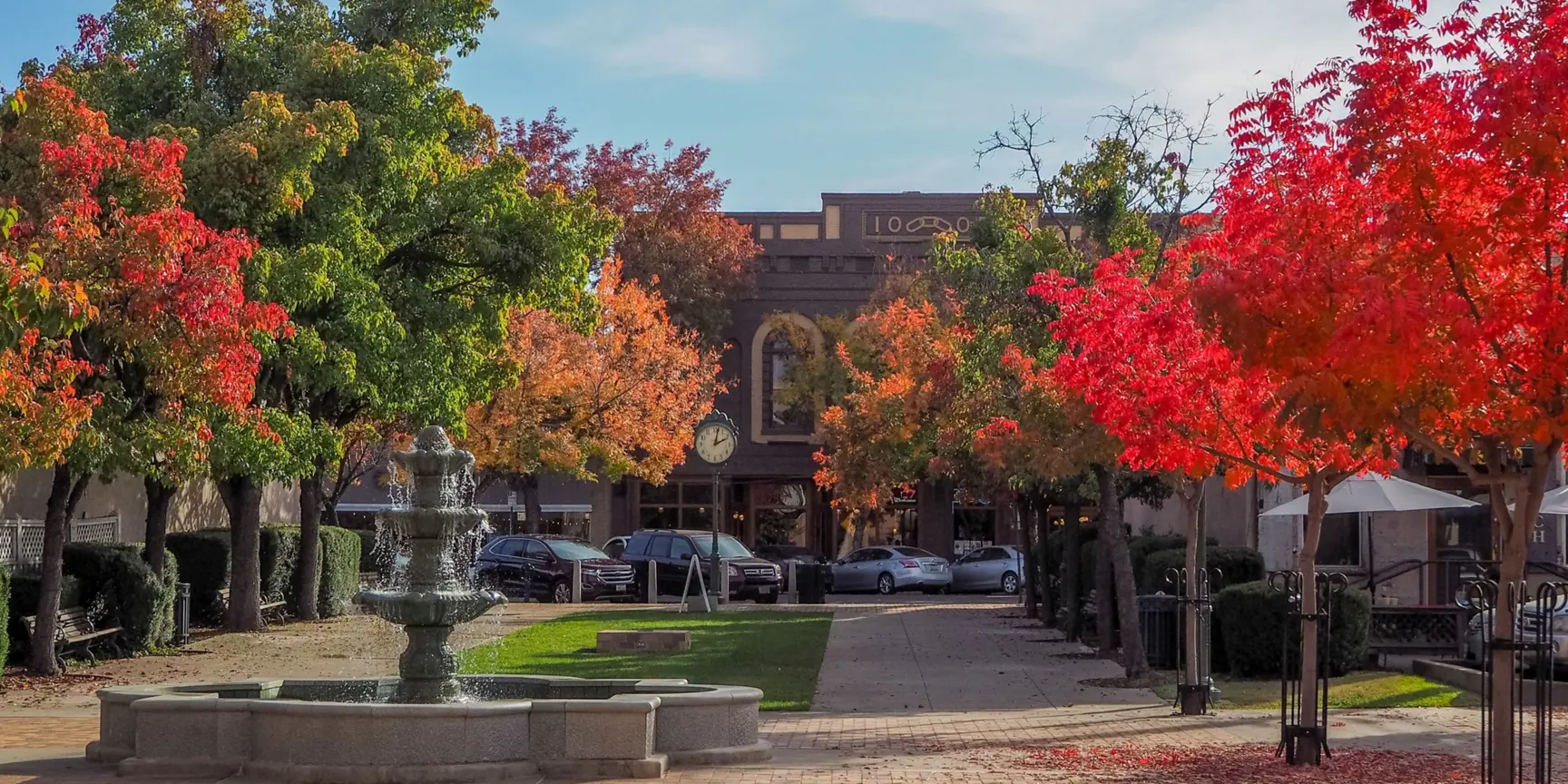 "Water fountain and brick building with trees during autumn"