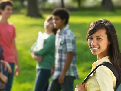 A teen in front of her friends turns and smiles at the camera
