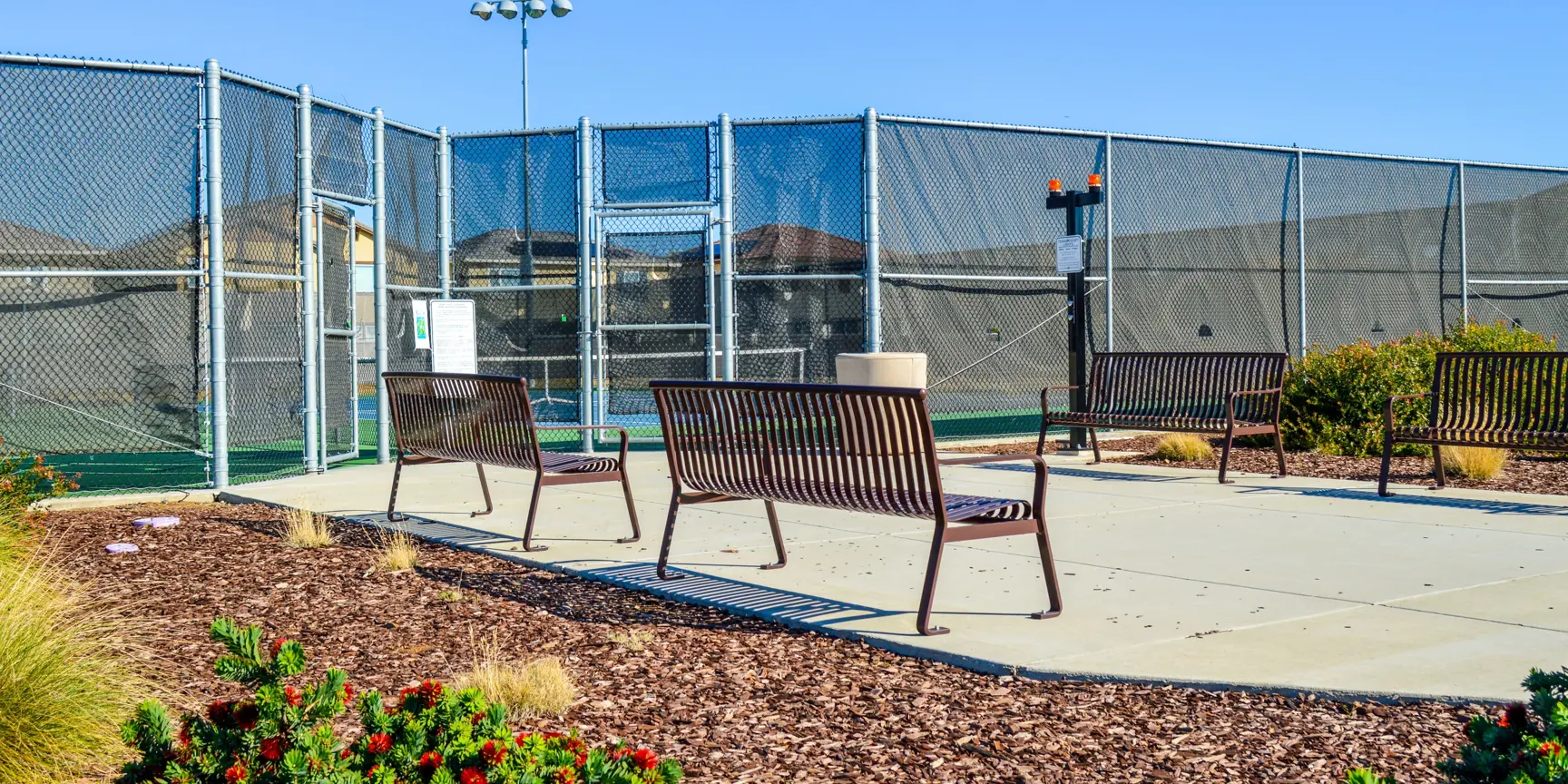 "Benches with tennis court behind and blue skies"